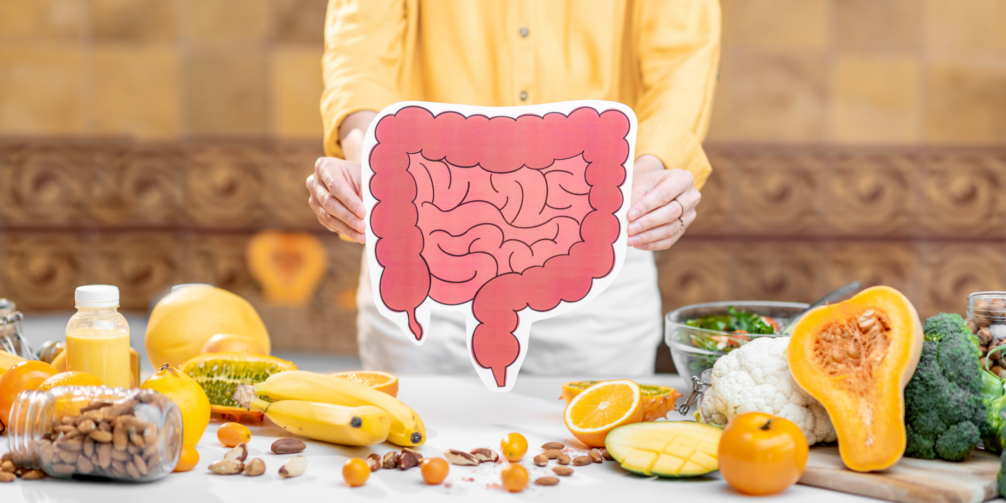 Picture of a woman in front of a table of fruit and veg holding a cartoon drawing of human guts.
