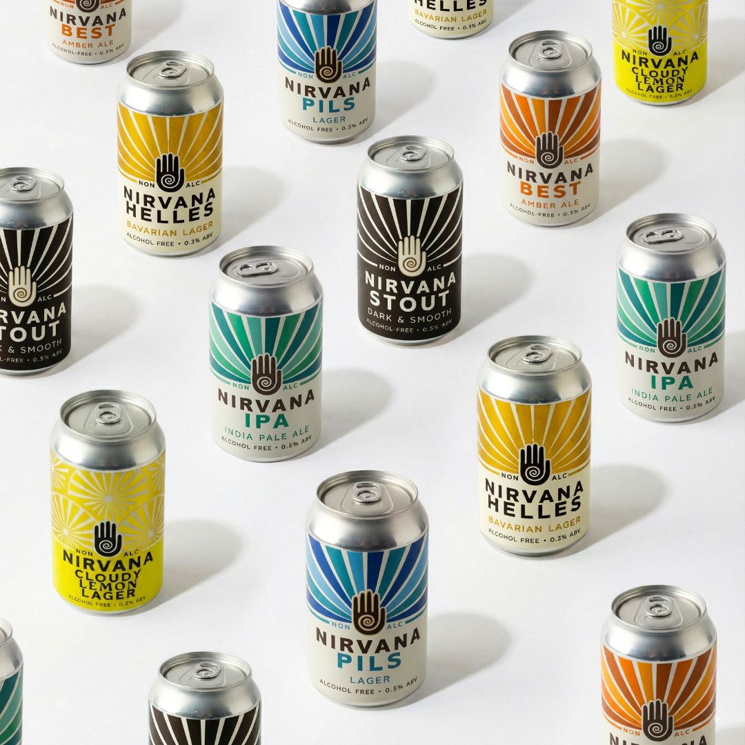 Multiple aluminum cans of Nirvana Hells Lager beer arranged on a white background, each can showing a different label color including yellow, teal, orange, black, and white.