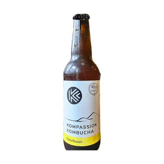 A brown bottle of Kompassion Elderflower kombucha with a white label and a yellow band.
