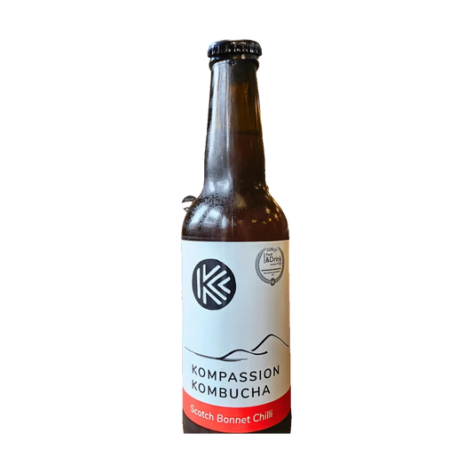 A brown bottle of Kompassion Scotch Bonnet Chilli kombucha with a white label and a red band.