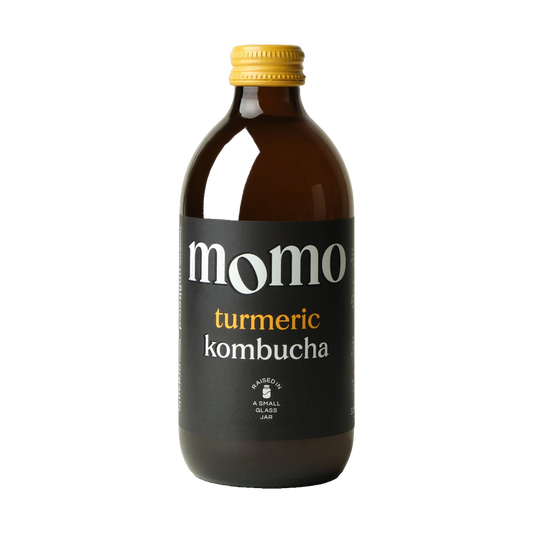 MOMO Turmeric raw kombucha in a brown glass bottle with a yellow cap and black label.