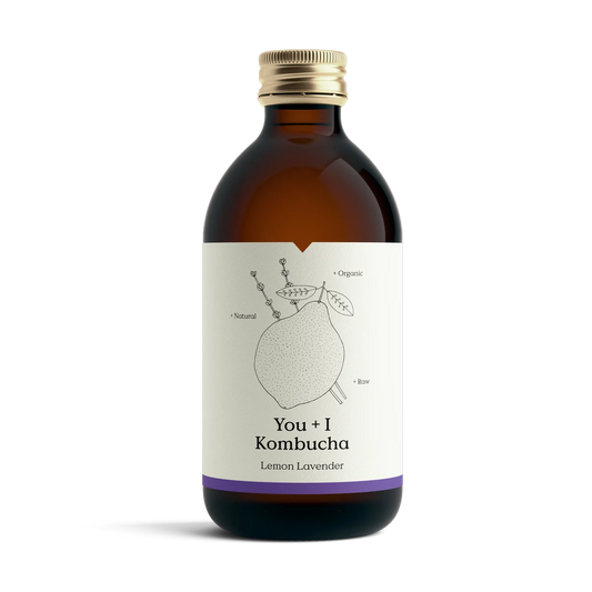 A brown bottle of You + I Lemon Lavender kombucha with a gold cap, a cream botanical label and a purple band.
