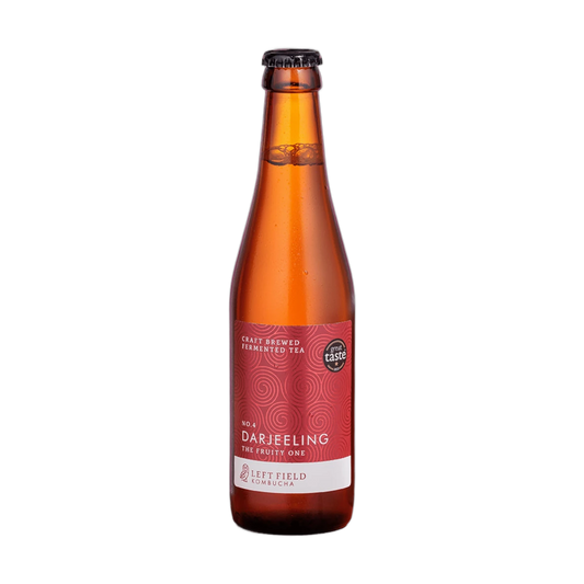 Left Field No.4 Darjeeling raw kombucha in a tall amber 330ml glass bottle with a black cap and a deep red swirl-patterned label.