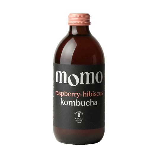MOMO Raspberry & Hibiscus raw kombucha in an amber glass bottle with a pink cap and a black label with pink lettering.