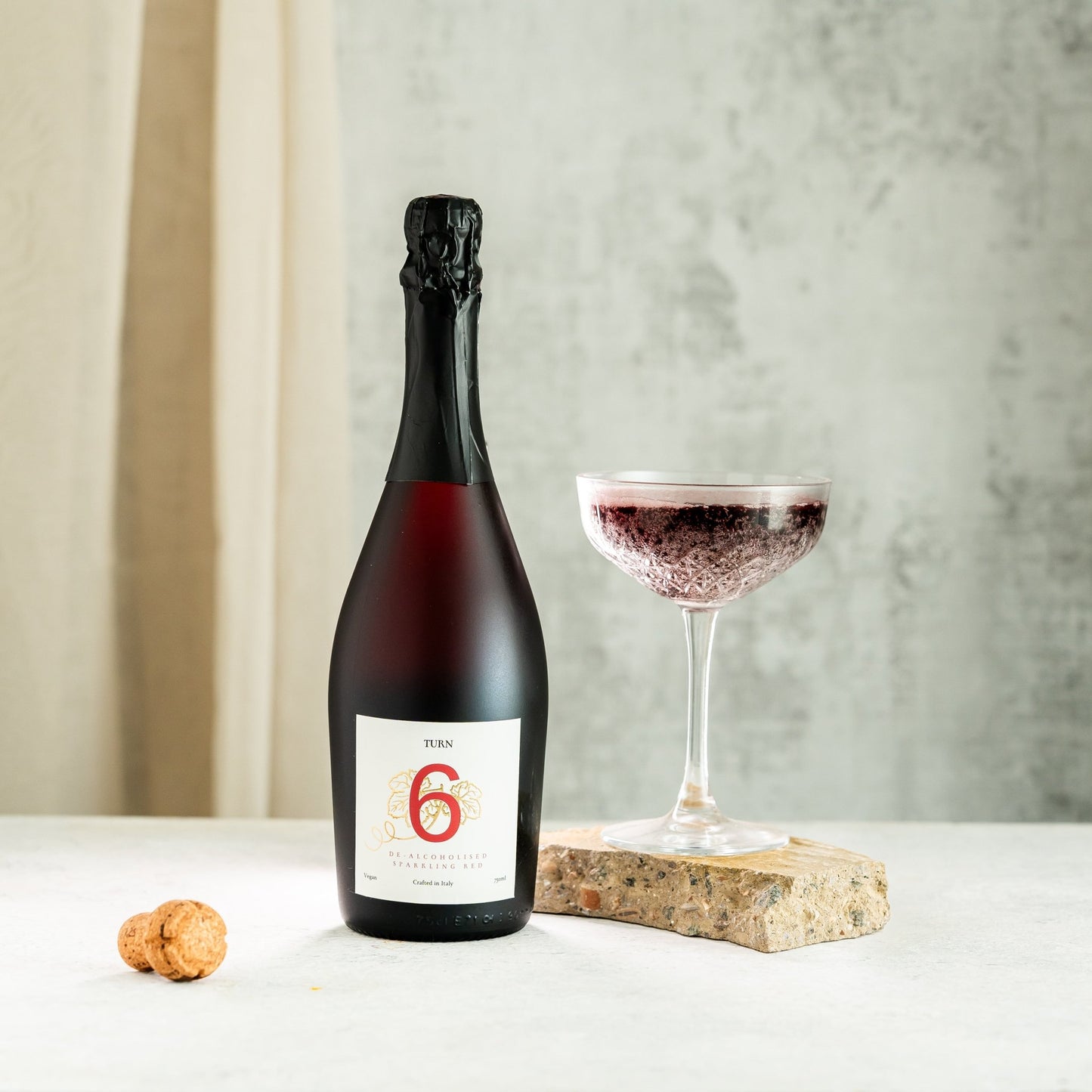 Bottle of red wine with a glass on a white surface