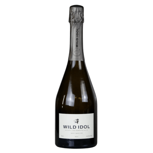 A bottle of Wild Idol sparkling wine with a white label and dark glass, sealed with a metallic silver foil capsule, set against a plain white background.