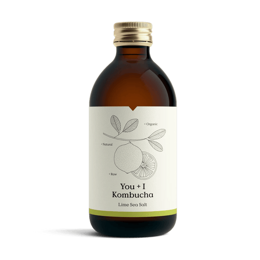 You + I Lime & Sea Salt raw kombucha in an amber glass bottle with a gold cap and a cream label with a botanical line drawing and a lime green band.